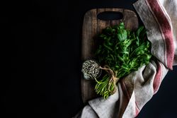 Arugula and sesame seeds on bread board with kitchen towel