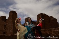 Native American woman and two Hispanic women standing beside an ancient site bGGBVb
