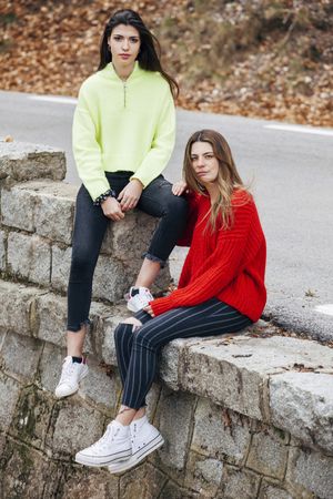 Women in sweaters sitting near road