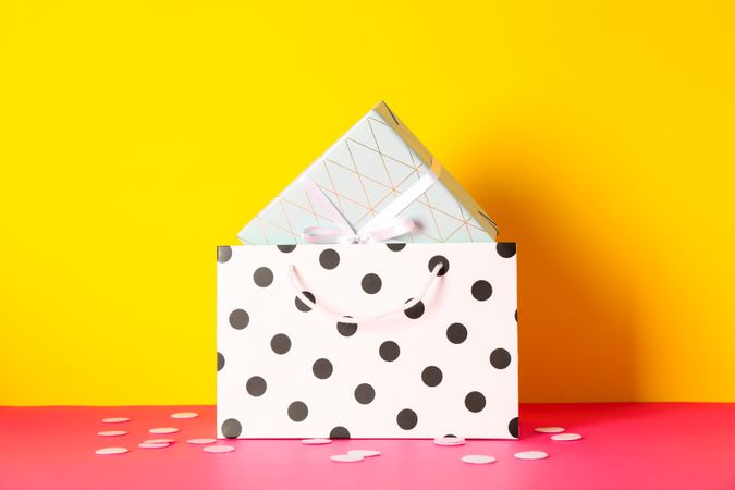Paper bag with present on multicolor background, space for text