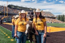 Two women with mascots prepare for at a University of Wyoming football game Laramie, Wyoming 0yXgqb