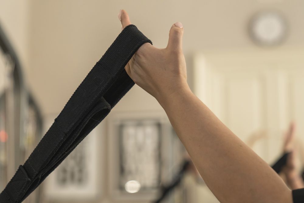 Close up of a woman's hand gripping a strap during a suspension strength training workout.
