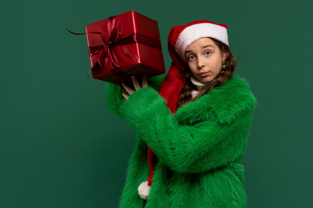 Girl in Santa hat and fur coat holding rgift box