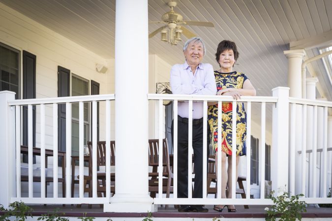 Chinese Couple Standing on Porch of Their House