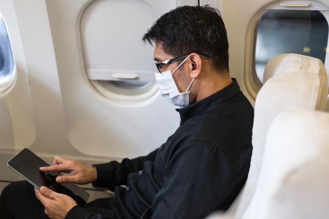 Businessman in suit using digital tablet in airplane