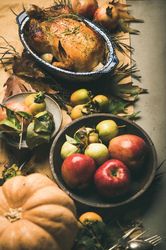 Roast turkey in decorative roasting pan, on table with fall leaves and fruit, vertical composition