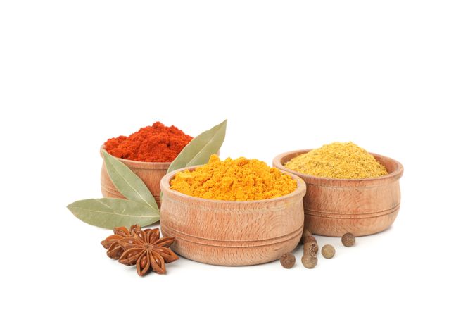 Side view of three wooden bowl full of different spices with bay leaf and anise