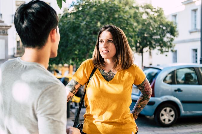 Modern multiracial couple talking while standing on street