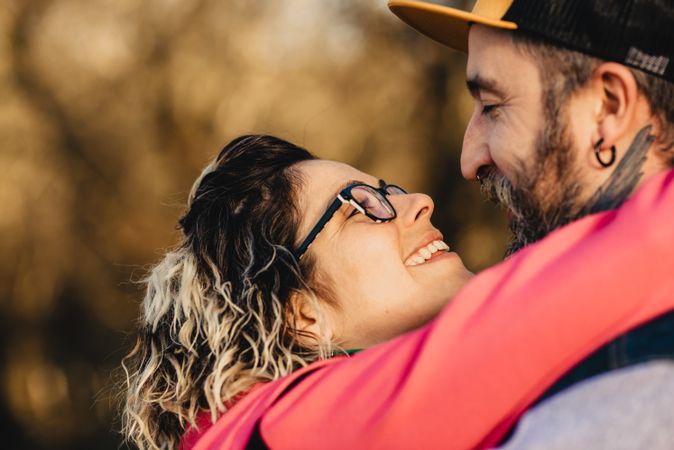 Happy couple hugging and kissing near tree in park