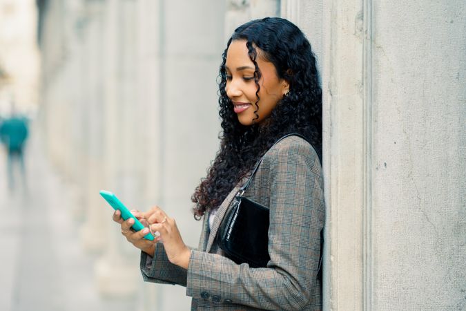 A young woman is engaged in using her smartphone while in a bustling urban environment