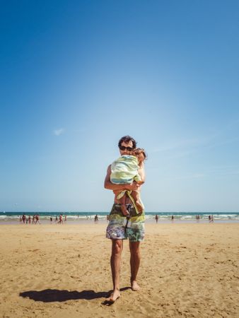 father holding little daughter at the beach
