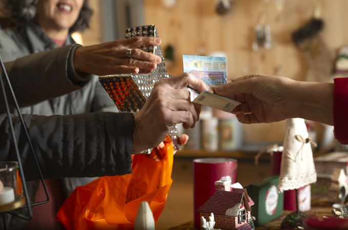 Crop woman with unrecognizable friend and shop owner making cash transaction