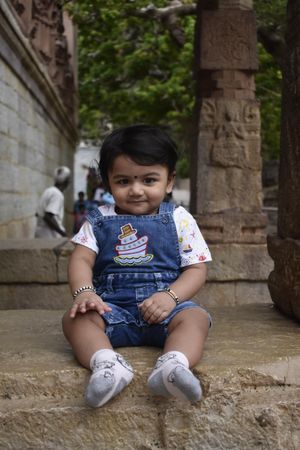 Young Indian child wearing denim sitting on the ground