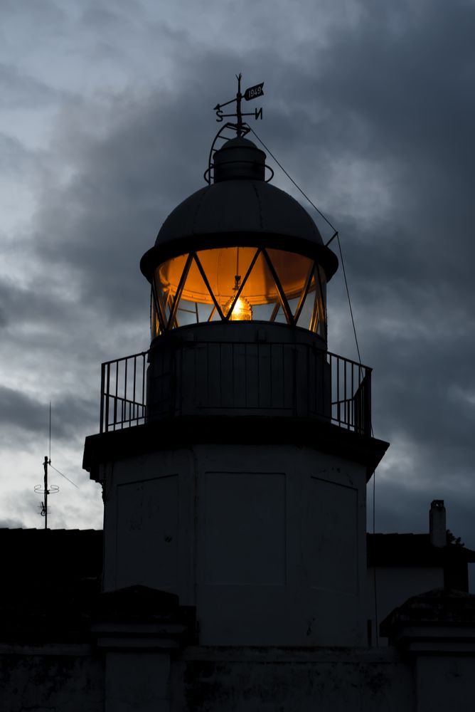 Shining lighthouse against cloudy sky