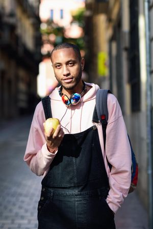 Vertical shot of male on European street eating an apple