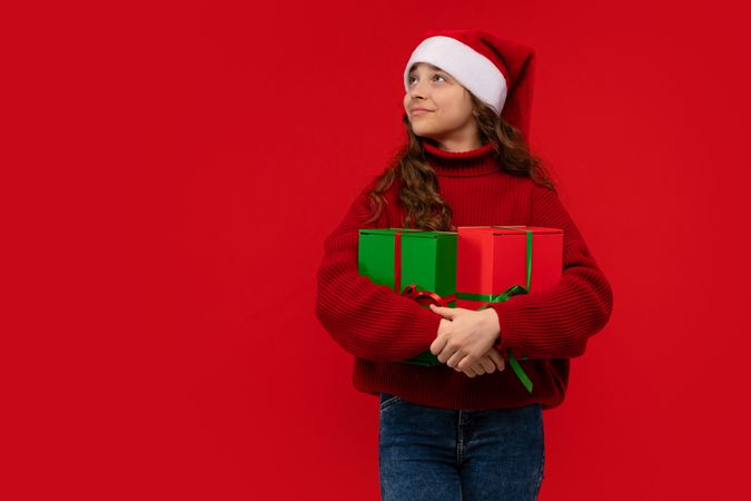 Girl in Santa hat holds Christmas gifts