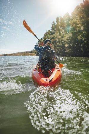 Rear view image of a mature man canoeing in a lake on a sunny day