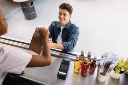 Female server handing to go meal to male customer