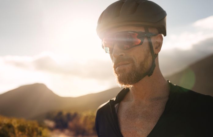 Male cyclist standing outdoors with sun shining