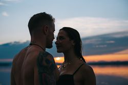 Couple hugging on beach of lake at sunset