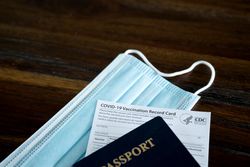 Close up of passport, vaccine card and mask
