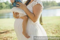 Pregnant woman in lace dress carrying a child bYkd15