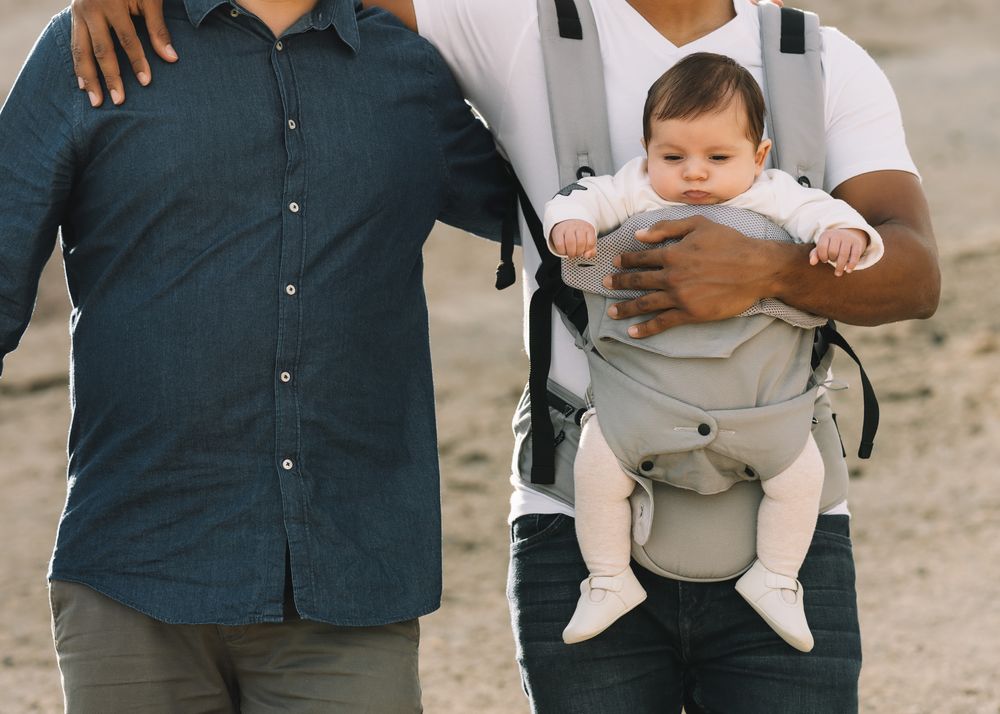 Unrecognizable diverse men walking with baby on nature