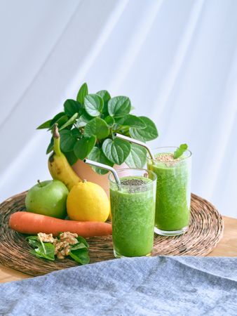 Green smoothies near assorted fruits