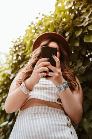Woman in hat smiling browsing smartphone
