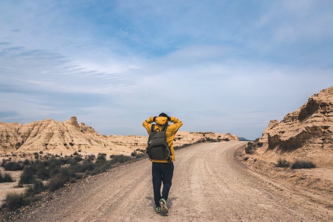 Man walking on road in desert hills