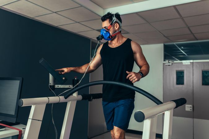 Runner with mask on treadmill in sports science laboratory in performance testing