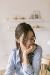 Woman sitting at a table resting her chin on her hand