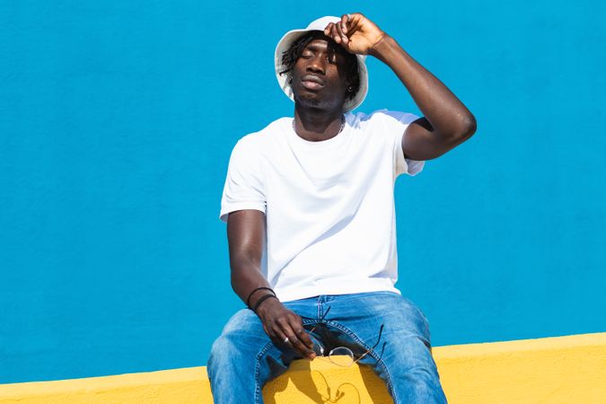Black man sitting on colorful wall