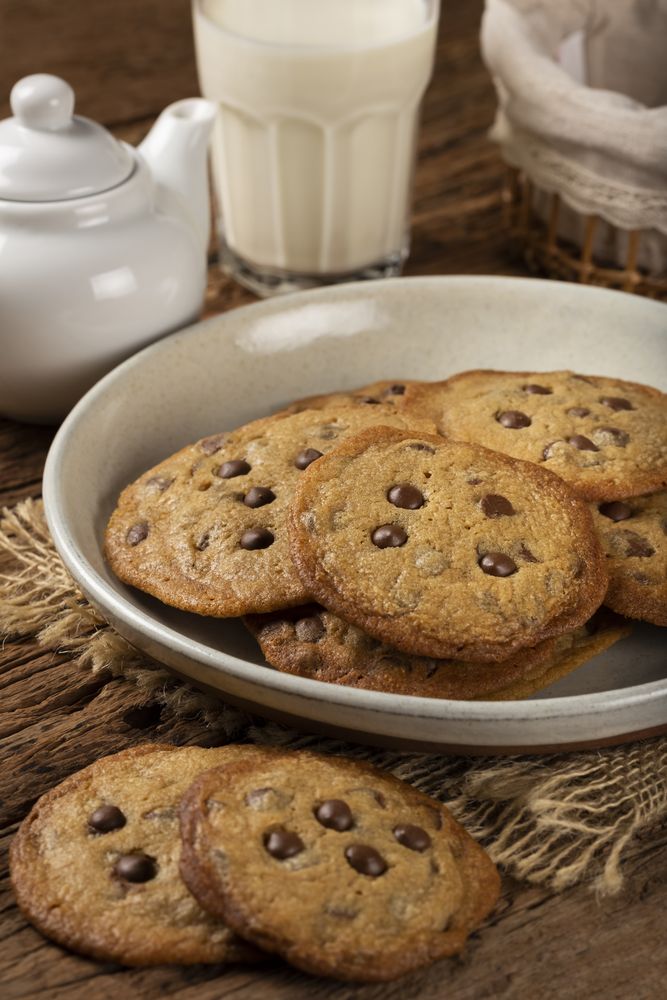 Delicious chocolate cookies with glass of milk on wooden table.