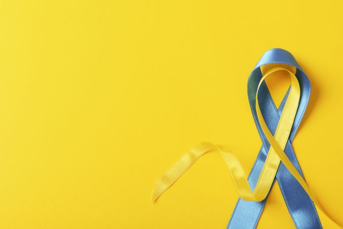 Ribbon in Ukrainian flag colors on yellow background with copy space