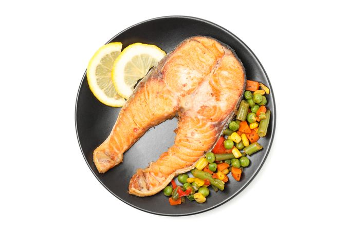 Plate with grilled salmon and vegetables isolated on blank background