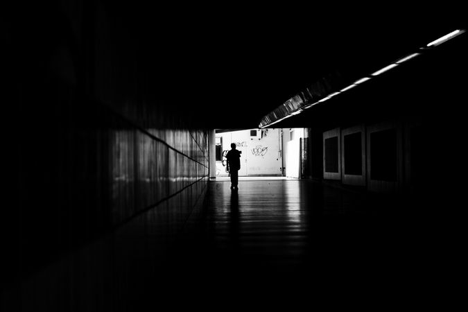 Silhouette of person walking through underground tunnel