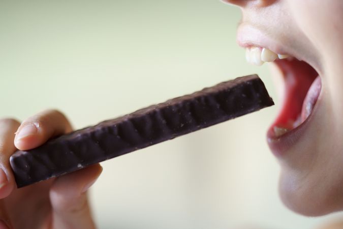 Anonymous girl with open mouth about to eat chocolate bar