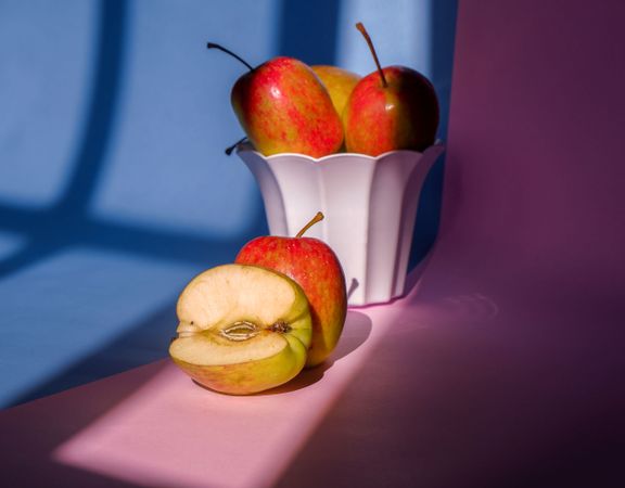 Photo of an apple in a container on a pink and blue background