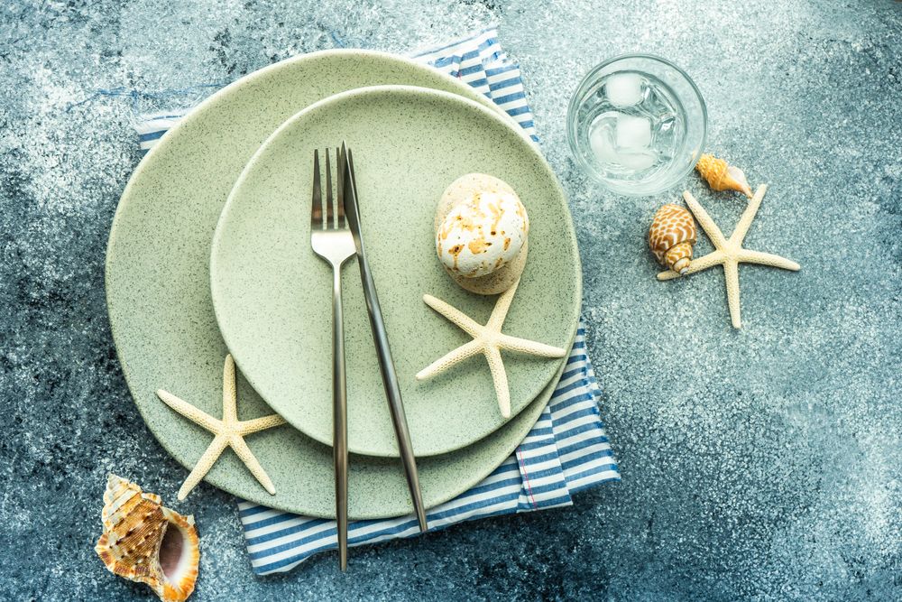 Summer concept with sea stars and shells on ceramic plate