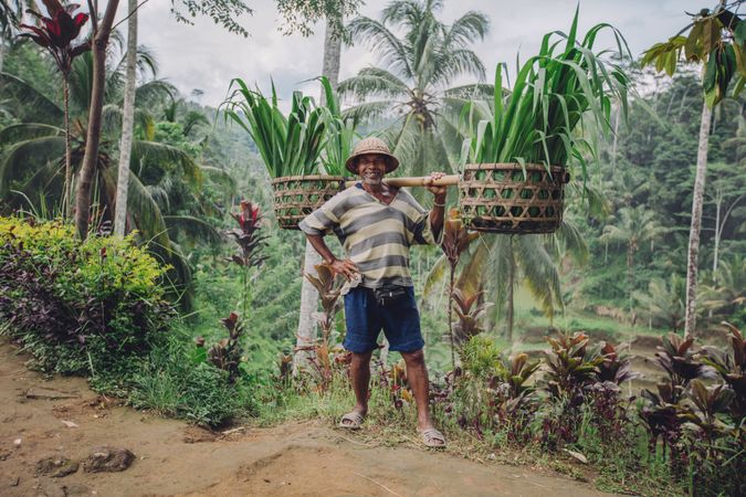 Full length shot of confident man carrying seedlings on his shoulders