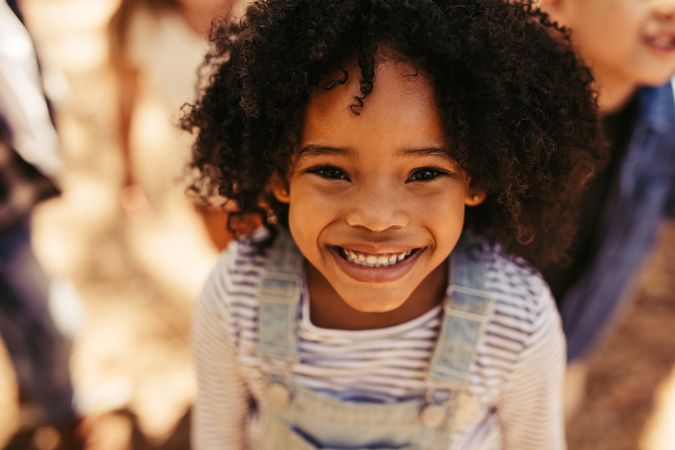 Close up portrait of smiling little girl with friends at background