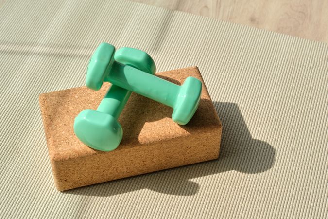 Dumbbells placed on yoga block on mat
