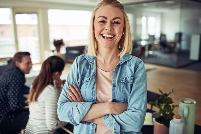 Portrait of blonde business woman smiling in an office with her arms crossed