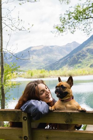 Female traveler with dog near lake in mountains