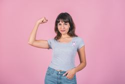 A woman wearing pink breast cancer awareness ribbon while showing arm muscle. Victory over breast cancer.