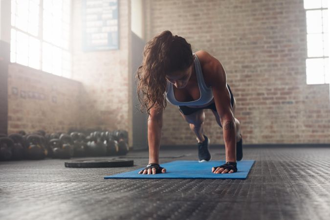 Young muscular woman doing core exercise on fitness mat in the gym