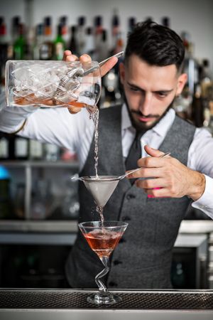 Bartender double straining a cocktail