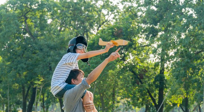 Father and son playing with toy plane in public park