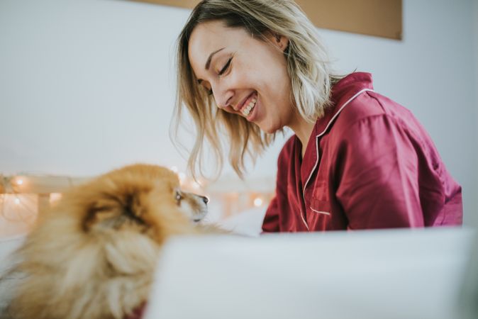 Smiling woman sitting in bed with dog